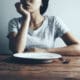 Woman with an Empty Plate Struggling with Eating Disorders