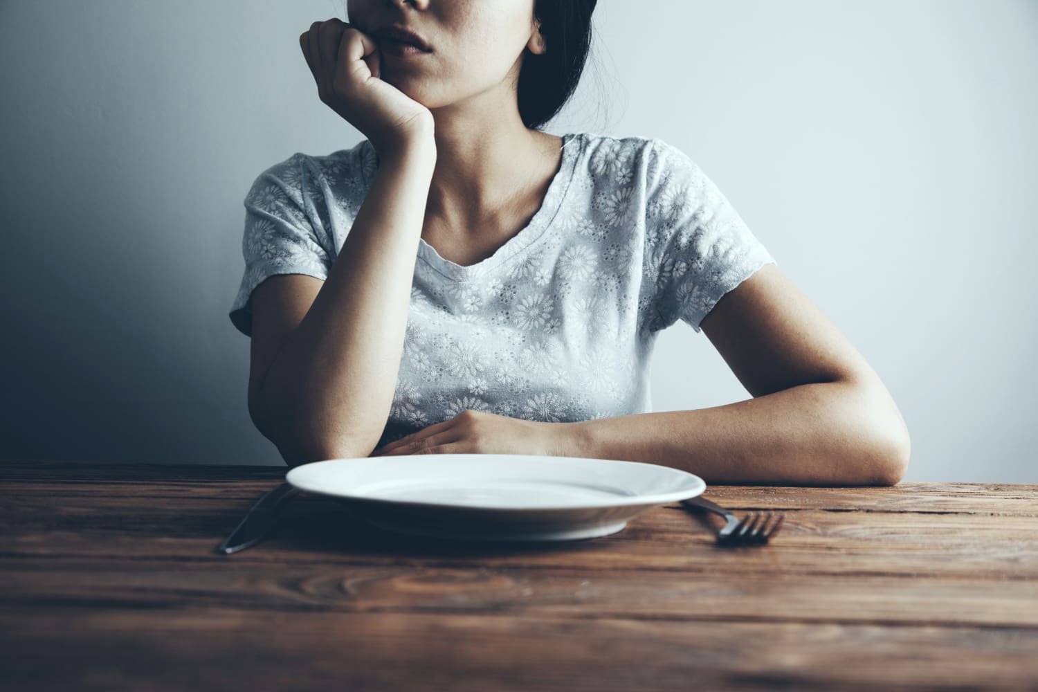 Woman with an Empty Plate Struggling with Eating Disorders