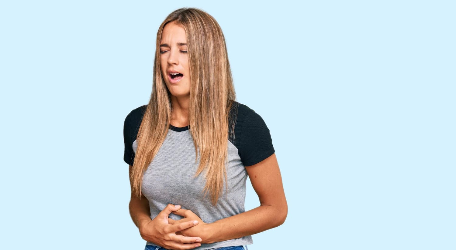 Young blonde woman wearing casual clothes with hand on stomach because nausea, painful disease feeling unwell