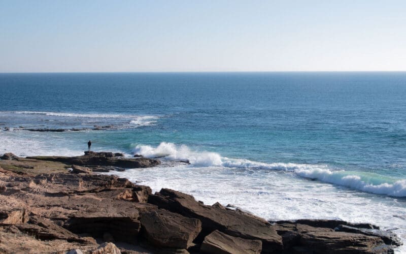A man gazes thoughtfully at the Atlantic Ocean, feeling a sense of solitude