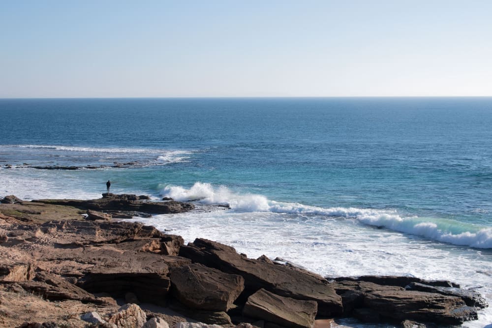 A man gazes thoughtfully at the Atlantic Ocean, feeling a sense of solitude