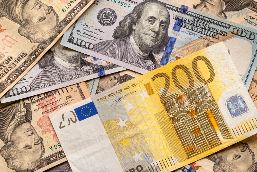 A 200 euro bill set against a vibrant abstract background of American dollar banknotes