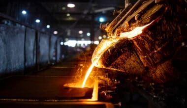 A bucket of hot molten iron is being poured into a mold during the industrial steel production process, which includes melting, molding, and foundry operations