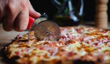 A chef slicing a pizza with a pizza cutter