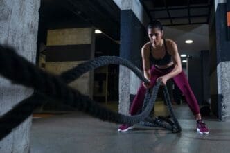 A fit woman exercising with battle ropes at the gym
