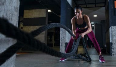 A fit woman exercising with battle ropes at the gym