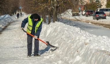 A man clears snow from the road with a shovel