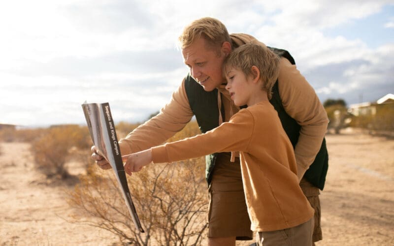 A medium shot of a child and an adult examining a sign in a foreign country.