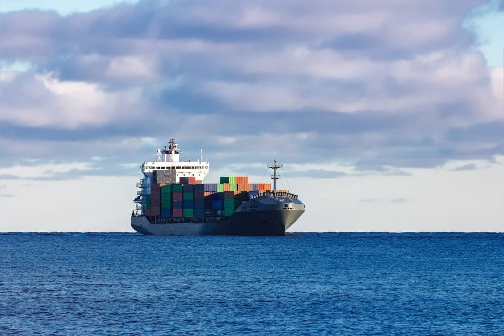 A modern gray cargo ship gliding smoothly across calm waters