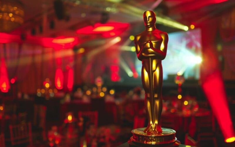 A red light shines behind an Oscar statue in a room illuminated by a red light event