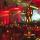 A red light shines behind an Oscar statue in a room illuminated by a red light event