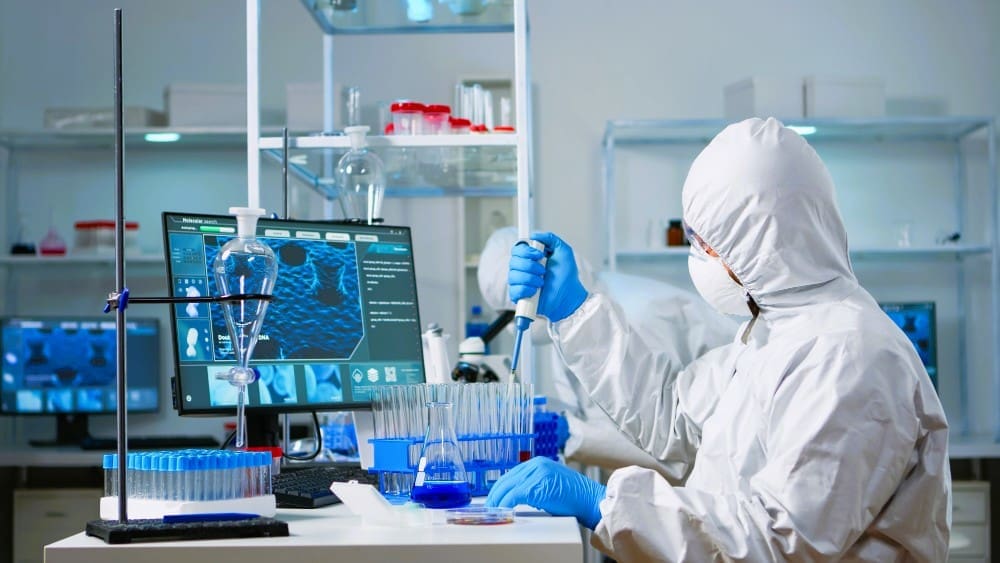 A scientist in a coverall is using a micropipette in a state-of-the-art laboratory