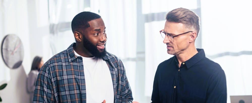 A wide-angle view of a smiling African American businessman engaging in conversation with his colleague