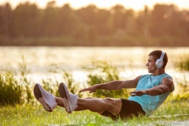 A young athletic man exercising outdoors by the riverside while enjoying music