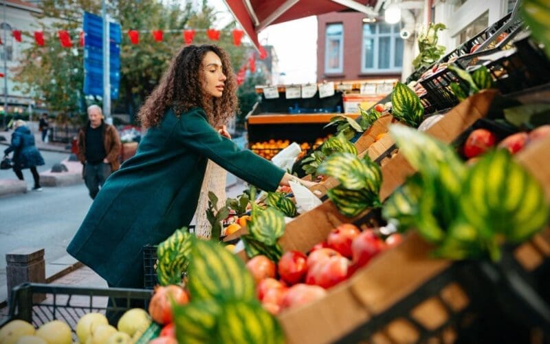 A young woman selecting items to purchase from a local farmers market stall in London