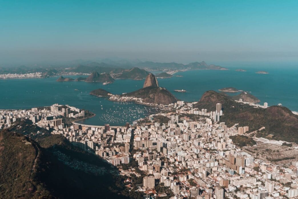 Aerial view of Rio de Janeiro, nestled between lush hills and the ocean, all beneath a clear blue sky