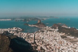Aerial view of Rio de Janeiro, nestled between lush hills and the ocean, all beneath a clear blue sky
