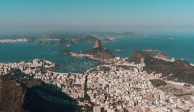 Aerial view of Rio de Janeiro, nestled between lush hills and the ocean, all beneath a clear blue sky