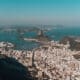 Aerial view of Rio de Janeiro, nestled between lush hills and the ocean, all beneath a clear blue sky