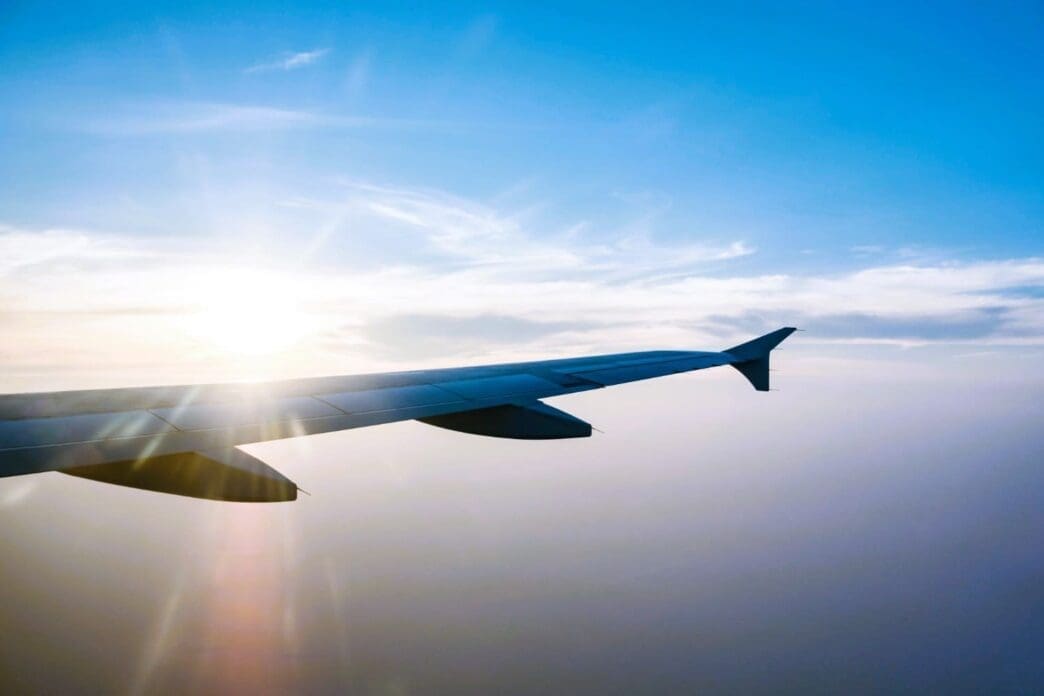 Airplane wing in flight during sunset against a blue sky