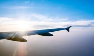 Airplane wing in flight during sunset against a blue sky