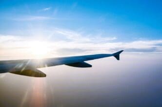 Airplane wing in flight during sunset against a blue sky