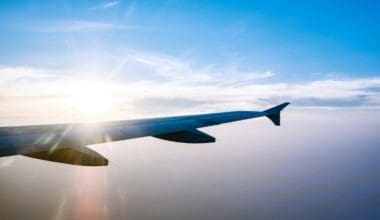 Airplane wing in flight during sunset against a blue sky