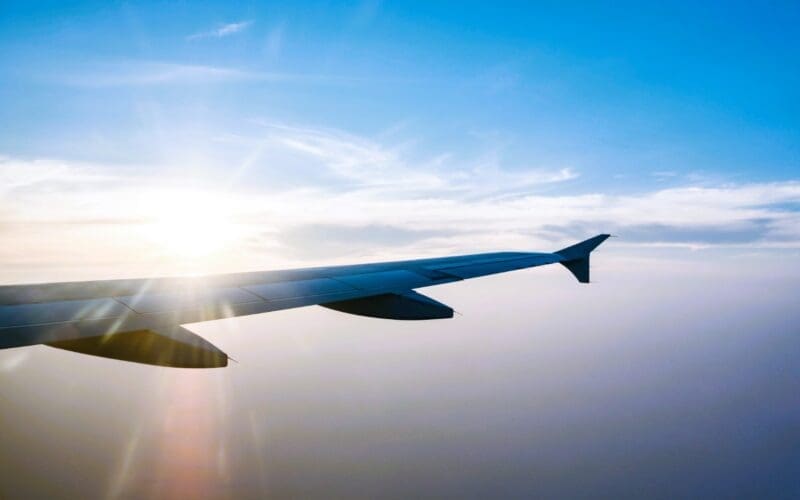 Airplane wing in flight during sunset against a blue sky