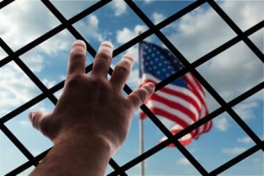 American flag displayed through wire mesh, symbolizing the concept of deportation