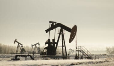 An oil field in Kazakhstan, dotted with pump jacks, is surrounded by lush greenery and bathed in sunlight