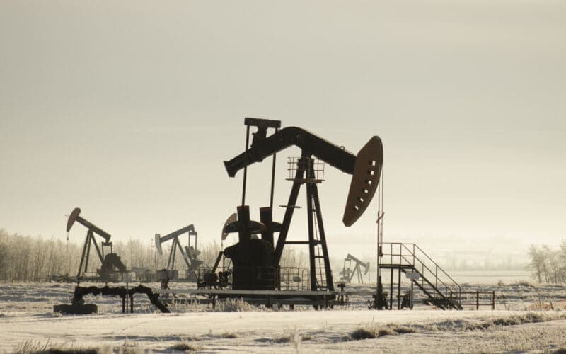 An oil field in Kazakhstan, dotted with pump jacks, is surrounded by lush greenery and bathed in sunlight