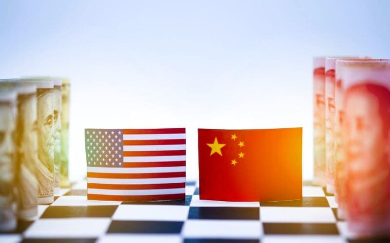 Close-up of a chessboard symbolizing the economic rivalry between the USA and China, featuring flags and currency from both nations