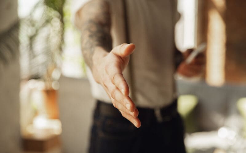 Close-up of a male hand extending in greeting, welcoming someone