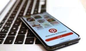 Close-up of an iPhone showcasing the Pinterest app alongside a MacBook laptop