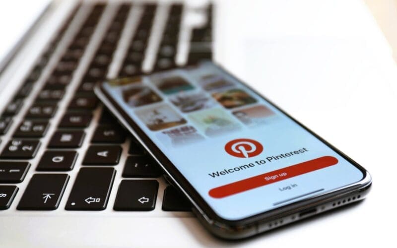 Close-up of an iPhone showcasing the Pinterest app alongside a MacBook laptop