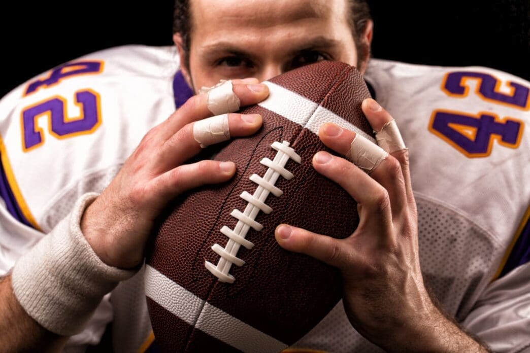 Close-up portrait of an American football player gently kissing the ball