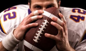 Close-up portrait of an American football player gently kissing the ball