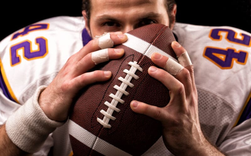 Close-up portrait of an American football player gently kissing the ball