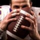 Close-up portrait of an American football player gently kissing the ball