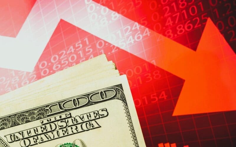 Concept of inflation, economic collapse, and stagnation depicted with the US dollar on a red stock chart featuring downward arrows