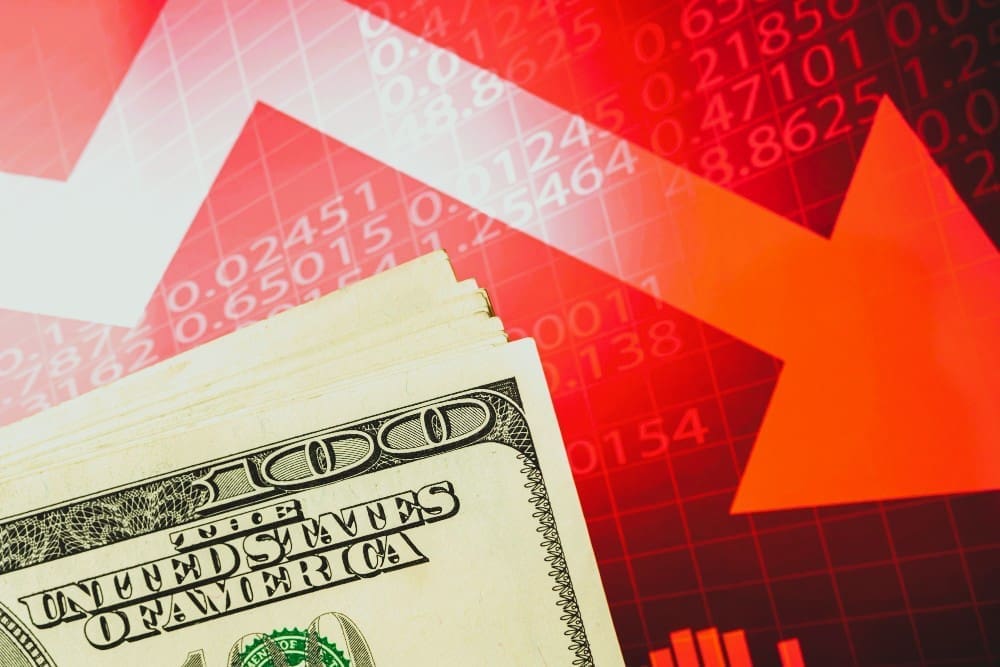 Concept of inflation, economic collapse, and stagnation depicted with the US dollar on a red stock chart featuring downward arrows