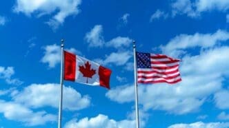 Flags of Canada and the USA against a backdrop of blue sky