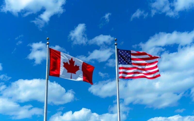 Flags of Canada and the USA against a backdrop of blue sky