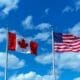 Flags of Canada and the USA against a backdrop of blue sky