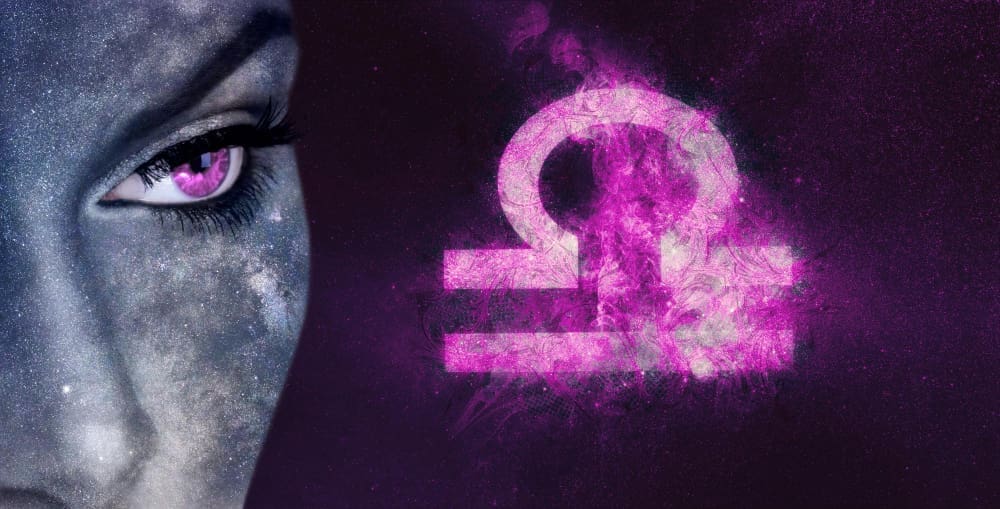 A close-up of a blue-toned face with a striking pink eye and subtle galaxy-like speckles on the skin, looking intensely forward. Beside it, a glowing, ethereal pink Libra zodiac symbol floats against a dark, starry, purple-hued background.
