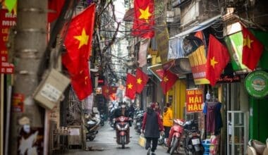 People go about daily life under Vietnamese flags in a narrow residential alleyway called Kham Thien Market in Hanoi, Vietnam