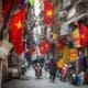 People go about daily life under Vietnamese flags in a narrow residential alleyway called Kham Thien Market in Hanoi, Vietnam