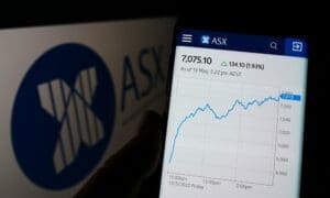 Person holding cellphone with webpage of Australian Securities Exchange Ltd (ASX) on screen in front of logo. Focus on center of phone display