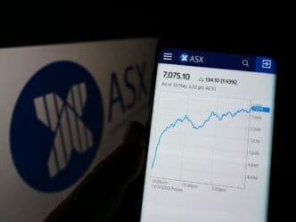 Person holding cellphone with webpage of Australian Securities Exchange Ltd (ASX) on screen in front of logo. Focus on center of phone display