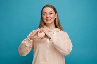 Smiling young blonde woman making a love sign that symbolizes a healthy heart